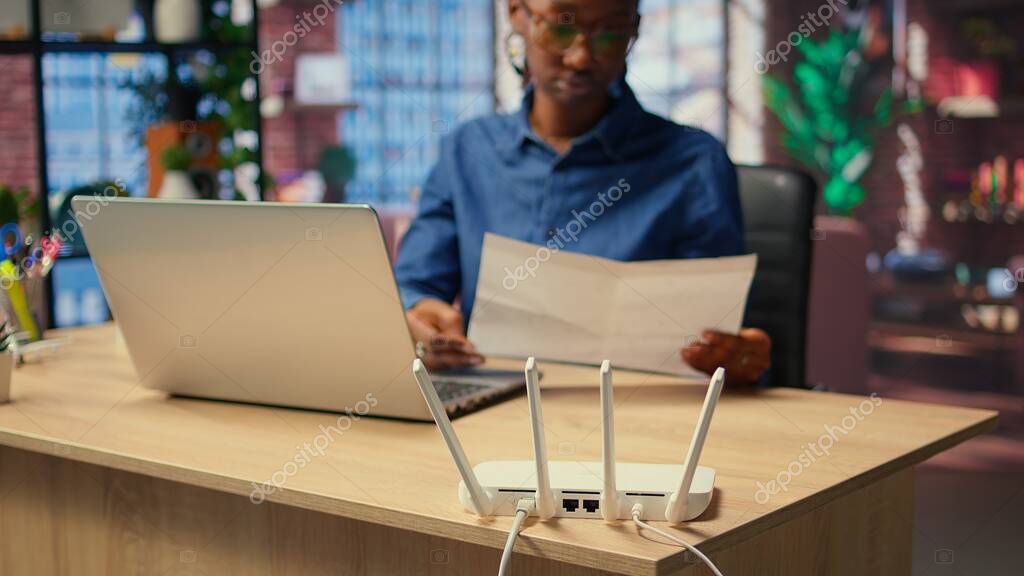 Professionista che lavora al laptop con router e dispositivi di rete